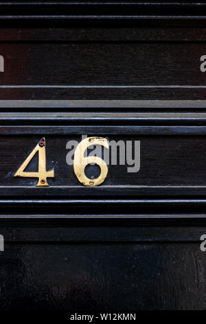 Haus Nummer 46 bei den sechsundvierzig in Metall Ziffern auf einem schwarz lackierten alte hölzerne Tür Stockfoto