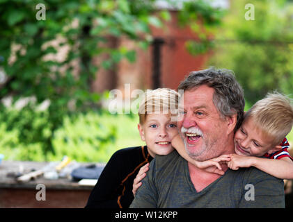 Porträt eines mittleren Alters Kaukasischen grauhaariger Mann mit einem Enkel im Garten Stockfoto