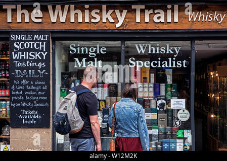 Ein junges Paar Blick in das Fenster der Whisky Trail Shop auf der High Street, Edinburgh, Schottland, Großbritannien. Stockfoto