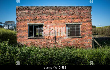 Ein verlassenes rotes Ziegelgebäude an einem Industriestandort. Stockfoto