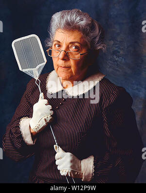 Alte Frau sehr wütend mit einem flyswatter Stockfoto