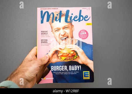 Paris, Frankreich, 19. Mai 2019: Mann Hand mit Liebe Zeitschrift von Edeka Supermarkt veröffentlicht mit glücklichen Menschen essen eine leckere Hamburger Stockfoto