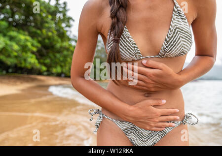 Magen bug travel Krankheit Frau touristische mit schmerzhaften Krämpfen am tropischen Strand - norovirus Magen-darm-Konzept. Krampf Schmerz Krankenversicherung. Stockfoto