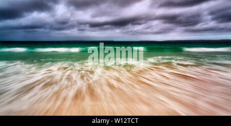 Breite seascape Panorama der smaragdgrünen Wellen unter Moody stürmischen Himmel rollen auf weißen Sand von Jervis Bay Beach auf NSW Pazifik Küste Australiens. Stockfoto