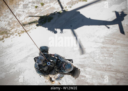 Zwei pararescuemen auf die 66Th Rescue Squadron Hoist, sich selbst aus der ein HH-60 Pave Hawk zugewiesen während des gemeinsamen zivilen Ausrichtung Konferenz (JCOC) 91 an der Nellis Air Force Base, Nev, 26. Juni 2019. Die JCOC wurde im Jahre 1948 gegründet als Verteidigungsminister - jährliche Outreach Program, in dem Geschäft und Gemeinschaftsführer Erfahrung militärischen Leben, Ausbildung und Arbeiten gefördert. (U.S. Air Force Foto von Airman 1st Class Jeremy Wentworth) Stockfoto