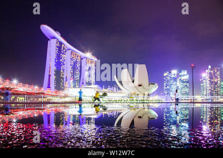 Singapur, Singapur - März 2019: Skyline von Singapur Marina Bay bei Nacht mit Marina Bay Sands und Kunst Science Museum in einem Teich spiegelt nach Ra Stockfoto