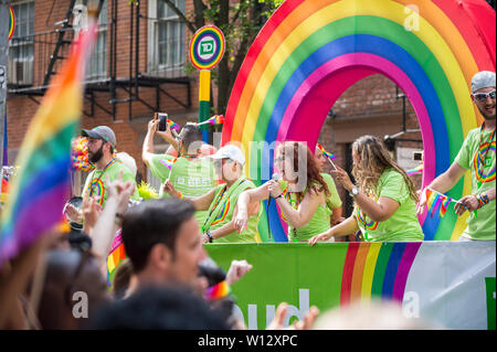 NEW YORK CITY - 25 Juni, 2017: Teilnehmer wave Flags auf einem Schwimmer, der mit einem Regenbogen Bogen von der TD Bank in der jährlichen Pride Parade gefördert im Dorf. Stockfoto