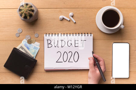 Frau Hand schreiben Neues Jahr Budget auf Notepad Stockfoto