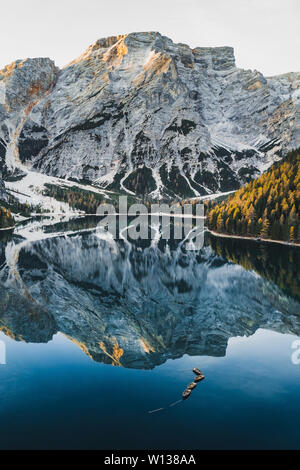 Herbst Landschaft des Lago di Pragser See in den italienischen Dolomiten in Norditalien. Drone Luftbild mit Booten aus Holz und schönen reflectio Stockfoto