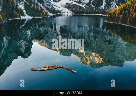 Herbst Landschaft des Lago di Pragser See in den italienischen Dolomiten in Norditalien. Drone Luftbild mit Booten aus Holz und schönen reflectio Stockfoto