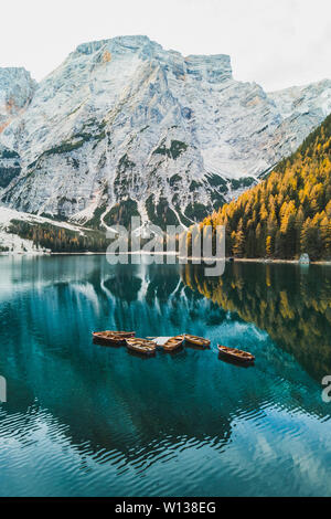 Herbst Landschaft des Lago di Pragser See in den italienischen Dolomiten in Norditalien. Drone Luftbild mit Booten aus Holz und schönen reflectio Stockfoto