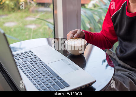 Legerer Mann arbeiten mit Laptop und trinken Kaffee im Cafe Stockfoto