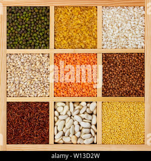 Verschiedene Arten von Grütze in eckigen Holzkasten, Sammlung von Rohdaten, Getreide, Bohnen und Samen, Ansicht von oben Texturen Stockfoto