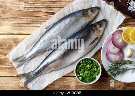 Gesalzene Heringe mit rotem Zwiebel, Zitronensaft und Gewürzen auf den alten hölzernen Tisch. Stockfoto