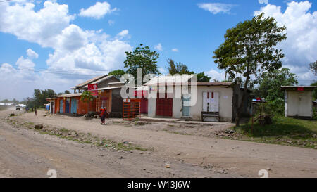 Moshi/Tansania, Kilimanjaro Provinz: 2. Januar 2016: Land Dorf aus Recyclingmaterial, das am Straßenrand in Tansania mit Geschäften und kleinen h Stockfoto