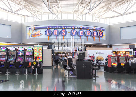 LAS VEGAS, Nevada, USA - 13. Mai, 2019: die Menschen spielen Spielautomaten am McCarran International Airport Terminal unter einem Willkommen in Las Vegas sign Stockfoto