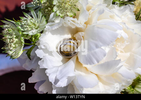 Braut und Bräutigam Weißgold Trauringe in der Mitte eines weiße Pfingstrose in einem brautstrauß. Stockfoto