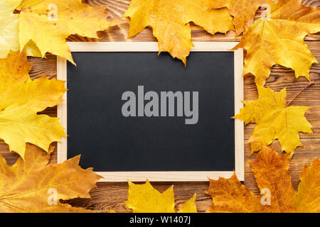 Gelbe ahorn Blätter um eine Tafel. Herbst oder Fallen saisonale Rahmen Hintergrund mit kopieren. Zurück zum Konzept der Schule. Stockfoto