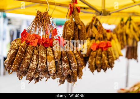 Getrocknete französische Würste, Salami, hängen vom Französischen Marktstand. Verschiedene Arten von kuriert Würstchen in Bündeln. Stockfoto