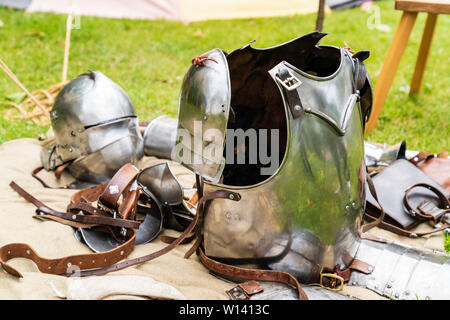 Mittelalterliche Geschichte Re-enactment Veranstaltung. Rüstungen auf Tisch, einschließlich Vorderzeug mit Trägern und hinter ein Deutscher Schaller Helm ca. 1490. Stockfoto