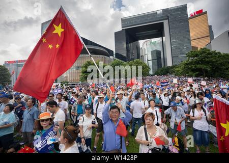 Ein pro Polizei Demonstrator winkt eine große chinesische Nationalflagge während der Rallye für die Unterstützung der Polizei. Zehntausende Demonstranten außerhalb der Regierung von Hongkong Sitz komplexe ihre Unterstützung der Polizei zu zeigen, da sie weitgehend gegen junge Demonstranten zu einem jetzt verschoben, um Auslieferungen auf dem Festland China erlauben dagegen gekämpft zu sammeln. Stockfoto