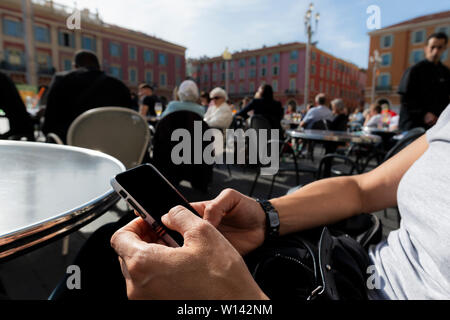 Frau (44 Jahre alt) mit Ihrem Smartphone auf einer Terrasse eines Coffee Shop, Handy mit schwarzen Bildschirm und Raum kopieren Stockfoto