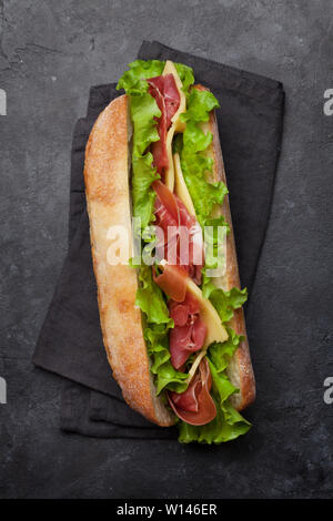 Frische submarine Sandwich mit Schinken, Käse und Salat auf dunklem Stein Hintergrund. Ansicht von oben Stockfoto