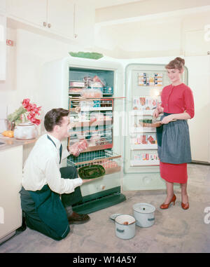 In der Küche der 1950er Jahre. Ein junges Paar in ihrer Küche Stolz zeigte die neue Frigidaire Gefrierschrank. ref BV 66-4 Stockfoto