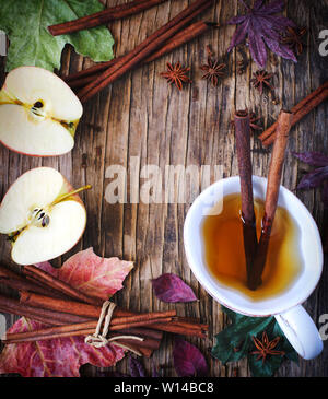 Heißes Getränk (Apple Tee, sider, Punch) mit Zimtstange, Sternanis und Nelke. Saisonale Glühwein trinken auf Holz- Hintergrund. Heißes Getränk und Äpfel für eine Stockfoto