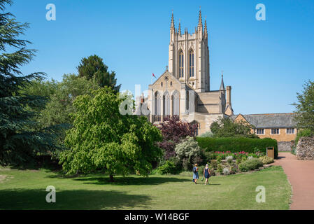 Abbey Gardens Bury St Edmunds, Aussicht im Sommer von zwei Frauen zu Fuß in Richtung St. Edmundsbury Cathedral in den Klostergärten, Bury St. Edmunds, Suffolk, Großbritannien. Stockfoto