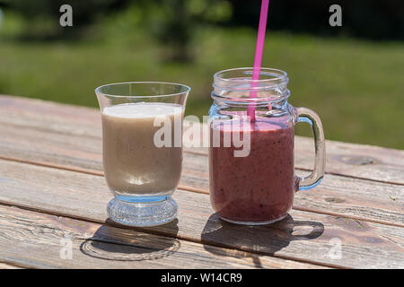 Gesunde Berry Smoothie mit Erdbeere und Banane in Gläsern, Outdoor, über die Natur Hintergrund. Stockfoto