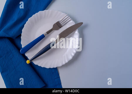 Flach essen Hintergrund mit leeren weißen Teller, Besteck und Servietten, über grauen Hintergrund. Stockfoto