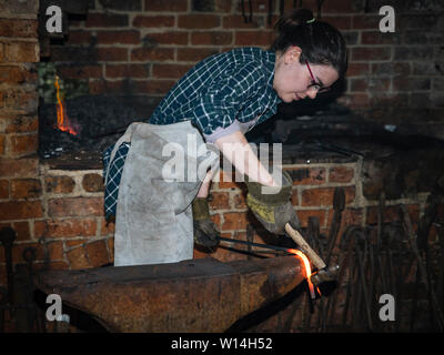 Eine weibliche Schmied hämmern ein Hot Steel Bar auf einen Amboss. Stockfoto