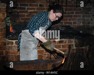 Eine weibliche Schmied hämmern ein Hot Steel Bar auf einen Amboss. Stockfoto