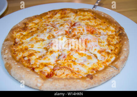 Frisch gebackenen Käse Pizza, appetitlich in Stücke schneiden liegt auf einem weissen Teller, Ansicht von oben. Stockfoto