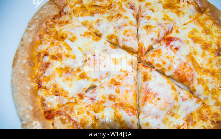 Frisch gebackenen Käse Pizza, appetitlich in Stücke schneiden liegt auf einem weissen Teller, Ansicht von oben. Stockfoto