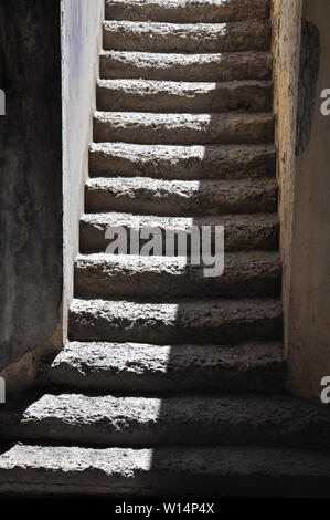 Schmale Treppe mit alten verwitterten Treppen halb sonnenbeschienenen aus einem Eingang hoch Stockfoto