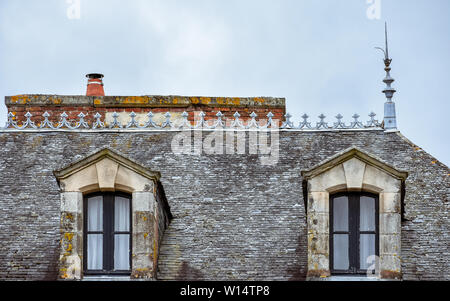 Dachgauben auf Schiefer Dach und orange Schornsteinen. Rochefort-en-Terre, Bretagne Stockfoto