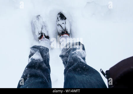 Der Mann Beine in Jeans und schwarze Schuhe draußen im Schnee Stockfoto