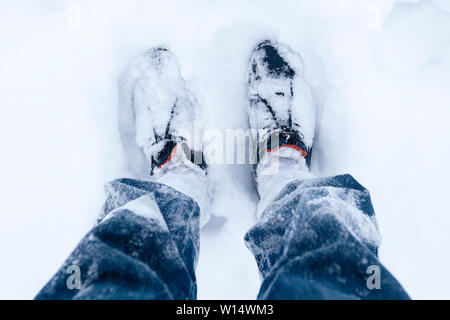 Der Mann Beine in Jeans und schwarze Schuhe draußen im Schnee Stockfoto