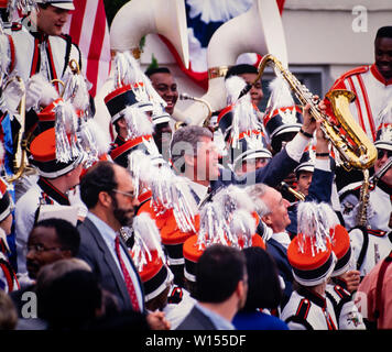 Präsidenten der Vereinigten Staaten Bill Clinton hält seine Saxophon aloft, als er mit einer marching band in Macon, Georgia im Jahre 1993 spielt. Clinton wird von US-Senator Wyche Fowler von Georgien verbunden. Stockfoto
