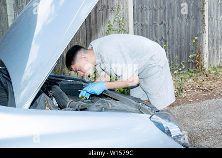 Teenage kaukasischen Jungen an einem Auto Motor Stockfoto