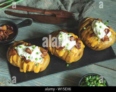 Gebackene Kartoffeln gefüllt mit Käse, Speck und Sauerrahm, geladen hasselback Kartoffeln Stockfoto