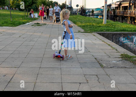 Belgrad, Serbien, 27. Juni 2019: Mädchen mit einem Kick Scooter stehen und warten auf den Rest Ihrer Familie an der Donau Riverside Promenade in Zemun Stockfoto