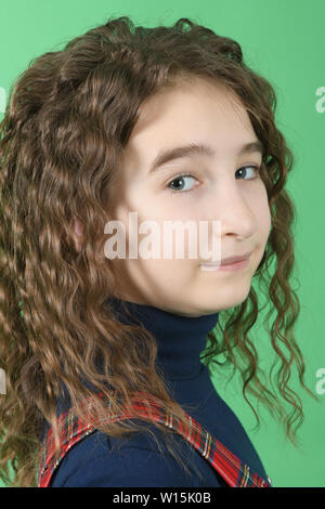 Portrait von adorable lächelnd Schulmädchen mit Haaren steht auf einem grünen Hintergrund isoliert Curl. Hochauflösendes Foto. Volle Tiefenschärfe. Stockfoto