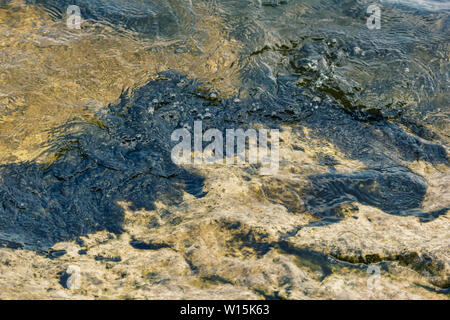 Natürliche flüssige Textur. Fluss Welle läuft auf der felsigen Ufer Stockfoto