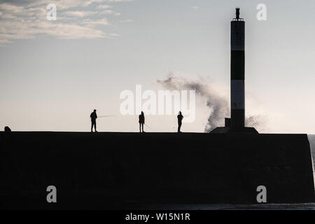 Aberystwyth, Wales, UK. Sonntag, 30. Jun 2019. UK Wetter: Leute angeln in der Nähe des Hafen Leuchtturm in Aberystwyth gespritzt bekommen durch die Wellen auf einer luftigen und kühlen Abend an der Westküste von Wales. Die Temperaturen sind stark von der rekordverdächtigen Höhen der letzten Tage Foto Keith Morris/Alamy Leben Nachrichten gefallen Stockfoto