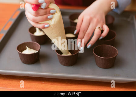 Attraktives Mädchen, Cupcakes, closeup Seitenansicht Foto. Frau lernt Cupcakes zu machen. Der Bäcker erstellt, köstliche Leckereien aus süßem Teig. Stockfoto