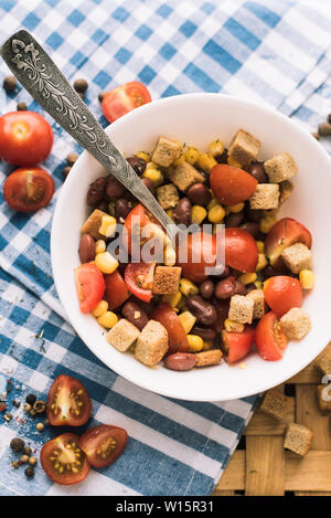 Salat von roten Bohnen, gelber Mais, Cracker. Picknickkorb und einen schönen blauen Handtuch. Stockfoto