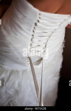 Braut von hinten. Schnürung das Hochzeitskleid. Stockfoto